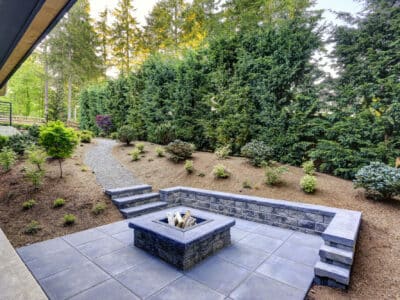 New modern home features a backyard with rectangular concrete fire pit framed by slate pavers and overlooking the lush garden. Northwest, USA
